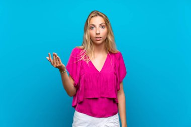 Izole mavi arka plan üzerinde Sarışın genç kadın şüphejest yapma