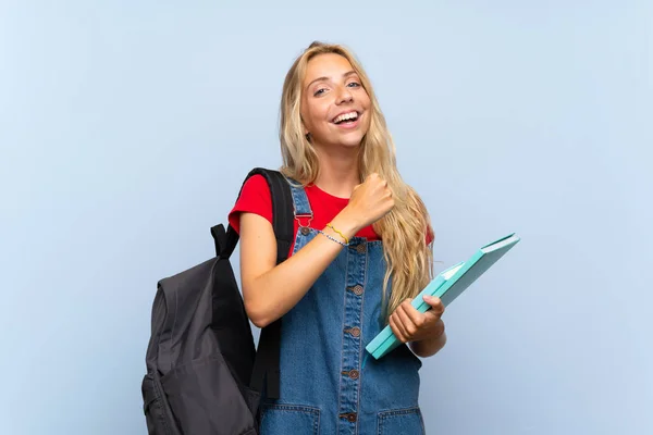 Jovem Loira Estudante Mulher Sobre Isolado Parede Azul Celebrando Uma — Fotografia de Stock