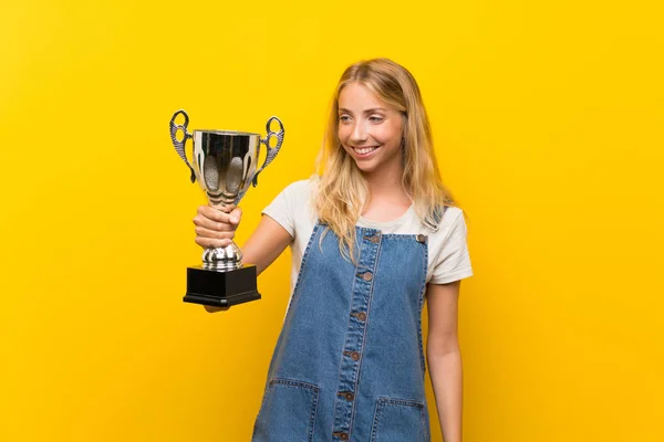 Blonde Junge Frau Über Gelbem Hintergrund Mit Einer Trophäe — Stockfoto