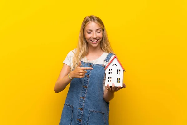 Blonde Jonge Vrouw Geïsoleerde Gele Achtergrond Houden Een Klein Huis — Stockfoto