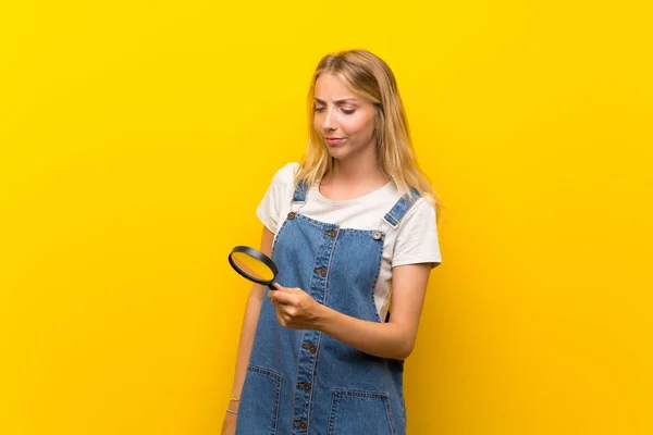 Blonde Junge Frau Über Isoliertem Gelben Hintergrund Mit Einer Lupe — Stockfoto