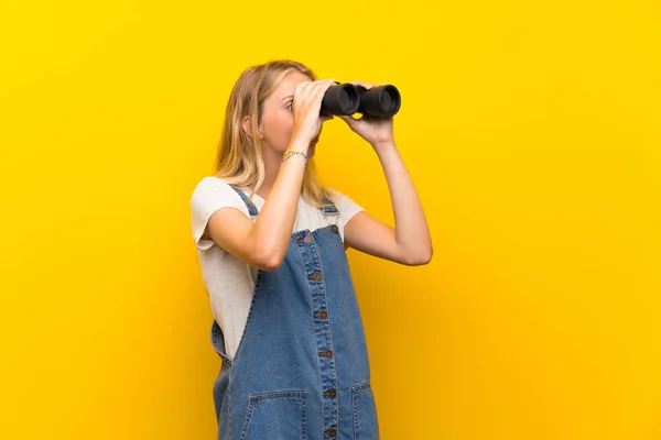 Mujer Joven Rubia Sobre Fondo Amarillo Aislado Con Binoculares Negros —  Fotos de Stock