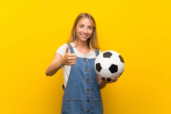 Loira Jovem Sobre Isolado Fundo Amarelo Segurando Uma Bola Futebol — Fotografia de Stock