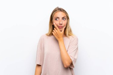 Izole beyaz arka plan üzerinde Sarışın genç kadın bir fikir düşünme