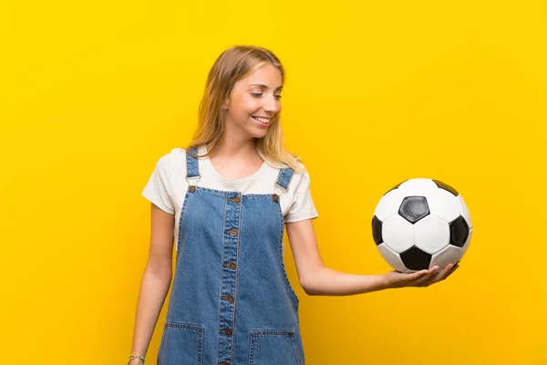 Loira Jovem Sobre Isolado Fundo Amarelo Segurando Uma Bola Futebol — Fotografia de Stock