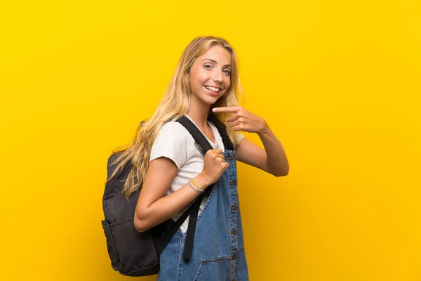 Jovem Loira Sobre Fundo Amarelo Isolado Com Mochila — Fotografia de Stock