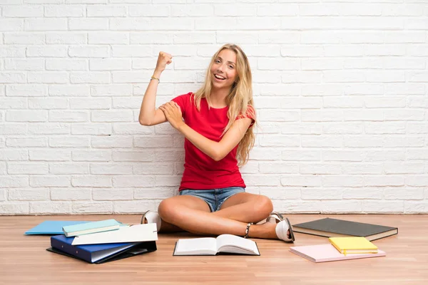 Joven Estudiante Rubia Con Muchos Libros Suelo Haciendo Gesto Fuerte — Foto de Stock