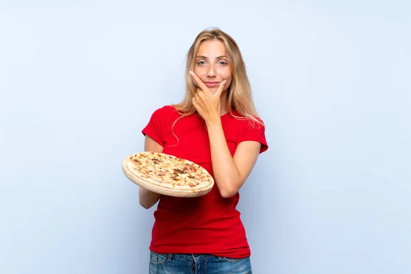Joven Rubia Sosteniendo Una Pizza Sobre Una Pared Azul Aislada — Foto de Stock