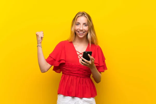 Jovem Loira Sobre Fundo Amarelo Isolado Usando Telefone Celular — Fotografia de Stock