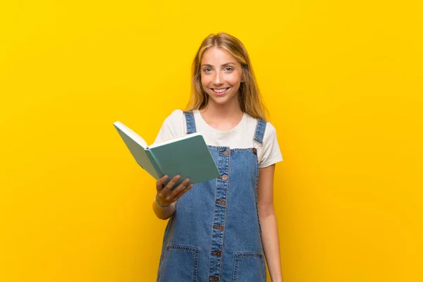 Mujer Joven Rubia Sobre Fondo Amarillo Aislado Sosteniendo Leyendo Libro — Foto de Stock