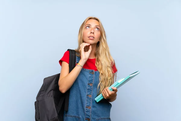 Young blonde student woman over isolated blue wall thinking an idea