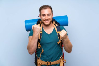 Mavi duvar üzerinde Hiker adam bir zafer kutluyor