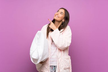 Genç Kadın Pijama ve soyunma elbise üzerinde izole mor arka plan ile işaret parmak büyük bir fikir