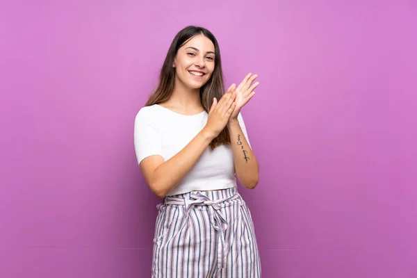 Young woman over isolated purple background applauding after presentation in a conference