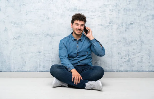 Młody Człowiek Siedzi Podłodze Pomocą Telefonu Komórkowego — Zdjęcie stockowe