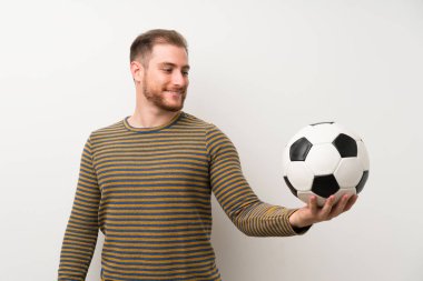 Bir futbol topu tutan izole beyaz duvar üzerinde yakışıklı adam