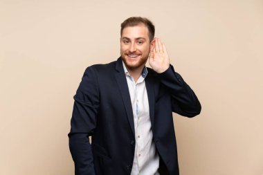 Izole arka plan üzerinde Sarışın adam kulak elini koyarak bir şey dinlerken