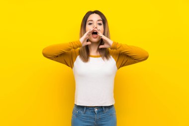 İzole sarı duvar üzerinde güzel genç kadın bağırmak ve bir şey duyurdu
