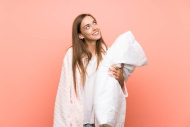 Pembe duvar üzerinde sabahlık genç kadın gülerek ve yukarı bakıyor