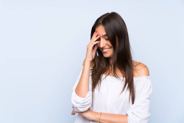 Genç bir kadın mavi arka planda gülüyor.