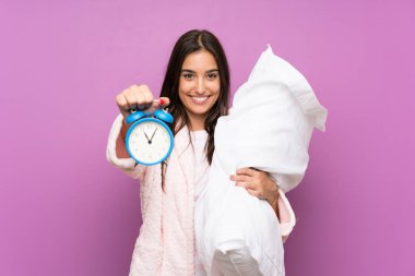 Pijama ve soyunma elbise içinde genç kadın izole mor arka planda tutan Vintage saat
