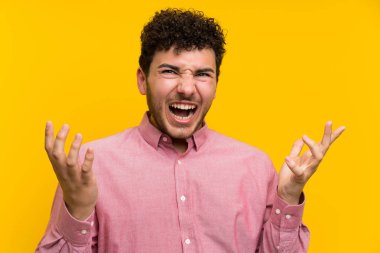 Izole sarı duvar üzerinde kıvırcık saçlı adam mutsuz ve bir şey ile sinirli