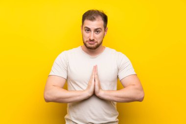 Sarı arka plan üzerinde yakışıklı adam yalvarıyor