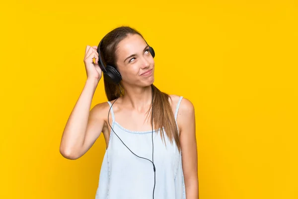Νεαρή Γυναίκα Ακούγοντας Μουσική Πάνω Από Απομονωμένο Κίτρινο Τοίχο Που — Φωτογραφία Αρχείου