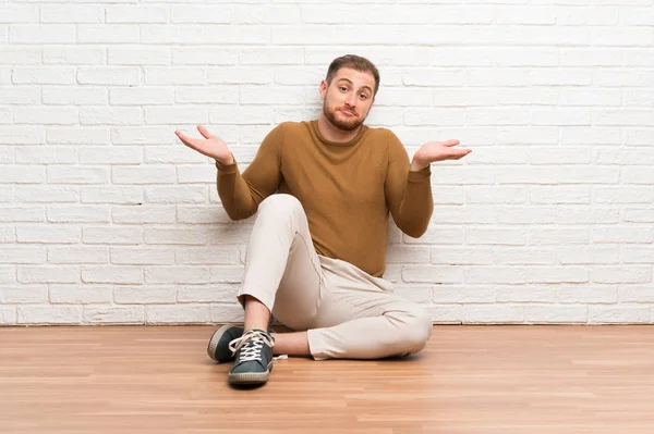Ξανθός Άνθρωπος Κάθεται Στο Πάτωμα Έχοντας Αμφιβολίες Σύγχυση Έκφραση Πρόσωπο — Φωτογραφία Αρχείου