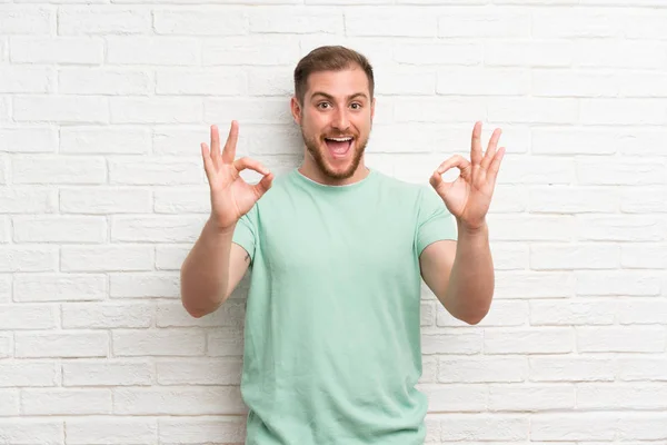 Blond Człowiek Ścianie Cegły Pokazując Znak Palcami — Zdjęcie stockowe