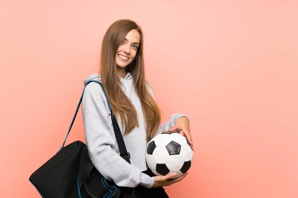 Happy Young Sport kobieta na białym tle różowy trzymając piłkę nożną — Zdjęcie stockowe