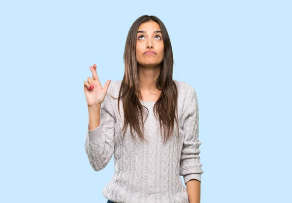 Young hispanic brunette woman with fingers crossing and wishing the best over isolated background