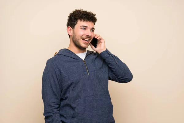 Muž Kudrnatými Vlasy Izolované Stěně Který Udržuje Rozhovor Mobilním Telefonem — Stock fotografie