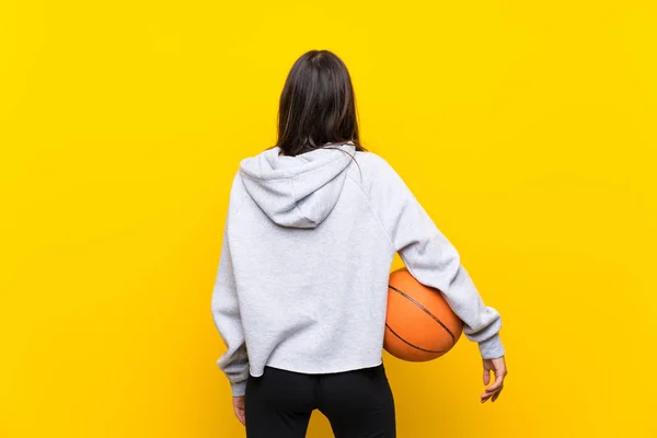 年轻女子在孤立的黄色背景上打篮球 — 图库照片