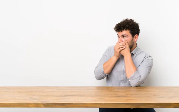 Joven Con Una Mesa Cubriendo Boca Mirando Hacia Lado —  Fotos de Stock