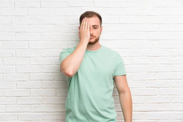 Blond Man Över Tegelvägg Som Täcker Ett Öga För Hand — Stockfoto