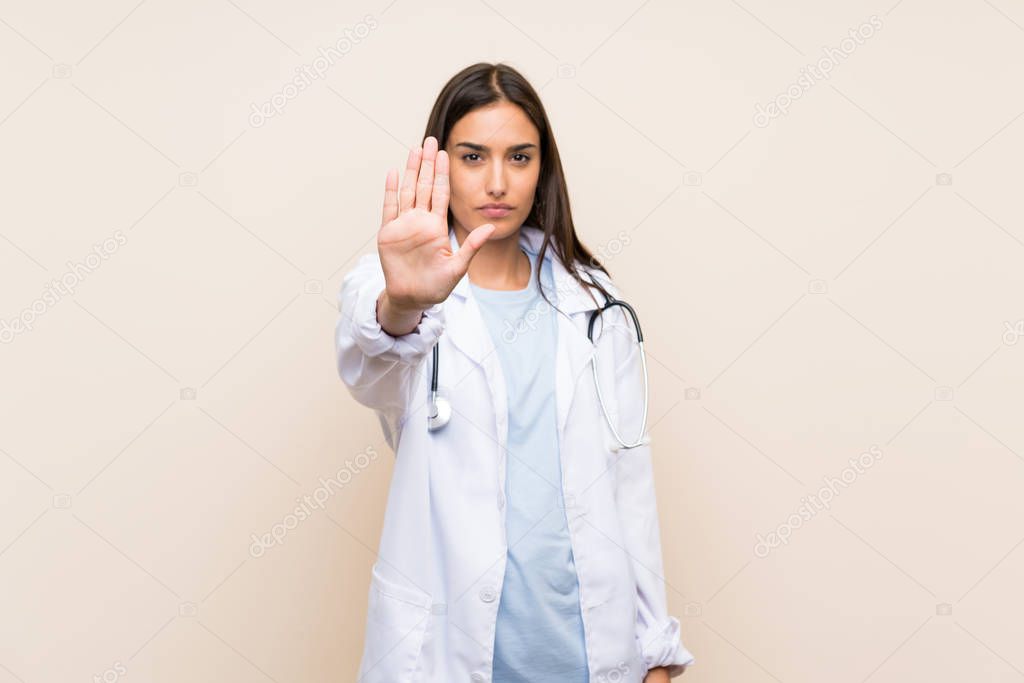 Young doctor woman over isolated background making stop gesture with her hand