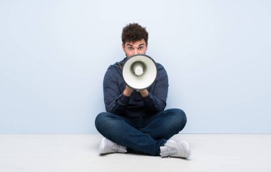 Bir megafon ile bağırarak katta oturan genç adam