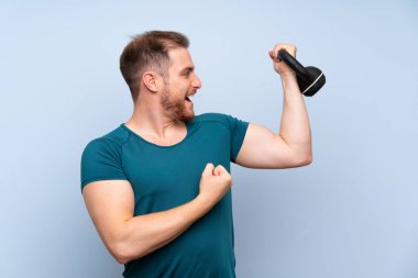 Kettlebell ile mavi duvar üzerinde sarışın spor adam