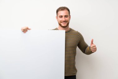 İzole beyaz duvar üzerinde yakışıklı adam eklemek için boş bir beyaz plasard tutan bir kavram