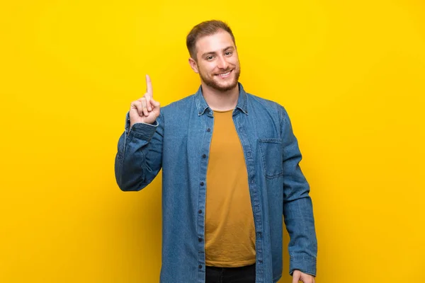 Blond Człowiek Nad Białym Murem Pokazując Podnosząc Palec Znaku Najlepszego — Zdjęcie stockowe