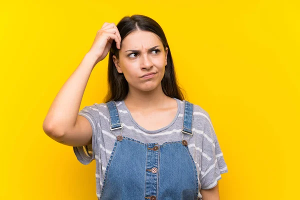 Jonge Vrouw Tuinbroek Geïsoleerde Gele Achtergrond Met Twijfels Met Verwarring — Stockfoto
