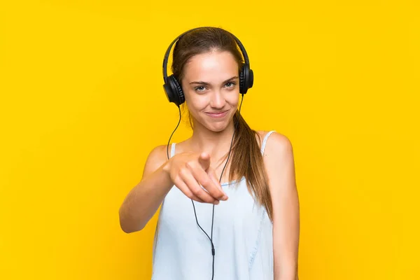 Mladá Žena Naslouchající Hudbu Přes Izolované Žluté Nástěnné Body Prstem — Stock fotografie