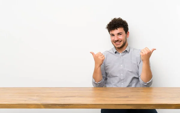 Νέος Άνθρωπος Ένα Τραπέζι Αντίχειρες Πάνω Χειρονομία Και Χαμογελαστά — Φωτογραφία Αρχείου