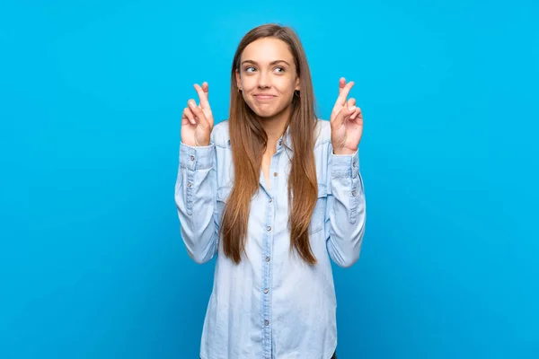 Jovem Mulher Sobre Fundo Azul Isolado Com Dedos Cruzando Desejando — Fotografia de Stock