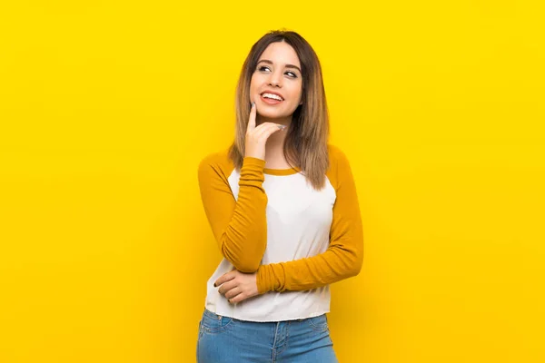 Mulher Bonita Sobre Parede Amarela Isolada Pensando Uma Ideia Enquanto — Fotografia de Stock