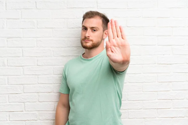 Blond Człowiek Ścianie Cegły Podejmowania Gest Stop Jej Ręki — Zdjęcie stockowe