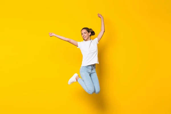 Mladá žena skákající přes izolovanou žlutou zeď — Stock fotografie