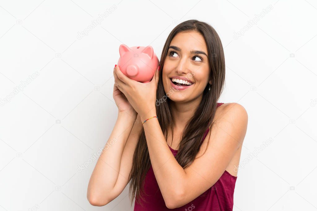 Young woman over isolated white background holding a big piggybank