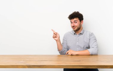 Yan parmak gösteren bir masa ile genç adam